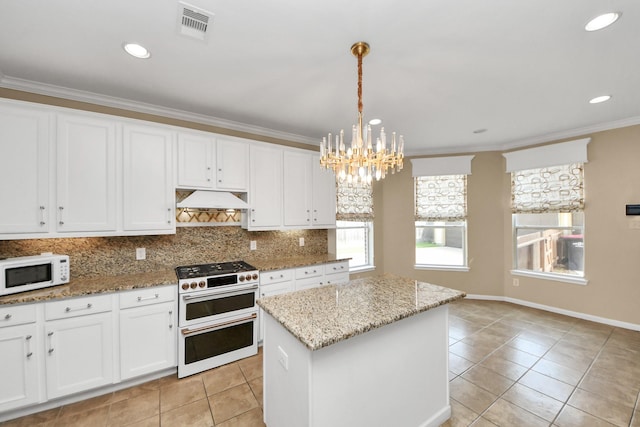 20902 Montana Bend Ln, Cypress, TX 77433 - kitchen with white appliances, under cabinet range hood, light tile patterned flooring, a chandelier, and crown molding