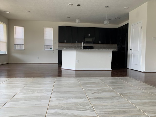 15815 Copper Oak Ln, Houston, TX 77084 - kitchen featuring black microwave, dark cabinets, open floor plan, and light stone counters