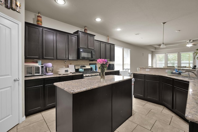 7455 Durango Creek Dr, Magnolia, TX 77354 - kitchen with black microwave, stainless steel gas stove, light tile patterned flooring, a kitchen island, and recessed lighting