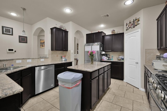 7455 Durango Creek Dr, Magnolia, TX 77354 - kitchen with stainless steel appliances, arched walkways, backsplash, light stone countertops, and recessed lighting