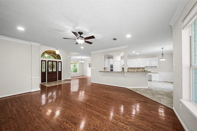 2452 Ripplewood Dr, Conroe, TX 77384 - unfurnished living room featuring a ceiling fan, recessed lighting, crown molding, light wood-type flooring, and a chandelier