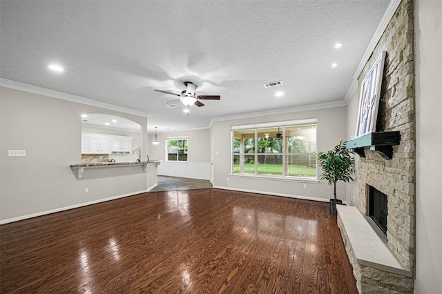 2452 Ripplewood Dr, Conroe, TX 77384 - unfurnished living room with a stone fireplace, a ceiling fan, crown molding, dark wood finished floors, and recessed lighting