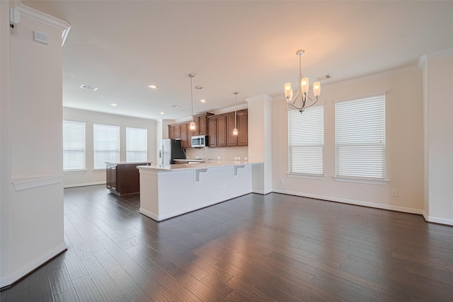 10004 Spring Shadows Park Cir, Houston, TX 77080 - kitchen featuring stainless steel microwave, freestanding refrigerator, a chandelier, light countertops, and brown cabinetry