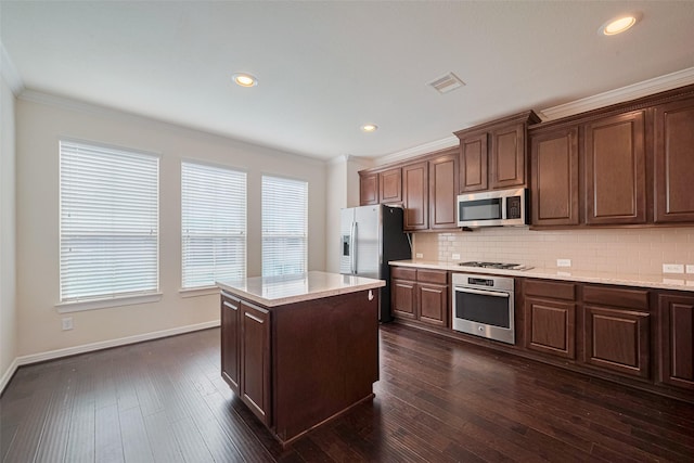 10004 Spring Shadows Park Cir, Houston, TX 77080 - kitchen featuring appliances with stainless steel finishes, ornamental molding, backsplash, healthy amount of natural light, and a kitchen island