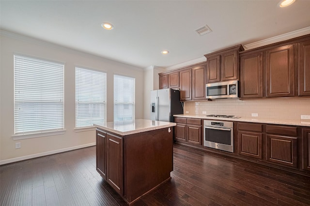 10004 Spring Shadows Park Cir, Houston, TX 77080 - kitchen with appliances with stainless steel finishes, ornamental molding, decorative backsplash, a center island, and dark wood finished floors