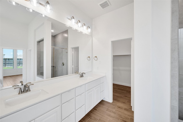30218 Indigo Falls Dr, Brookshire, TX 77423 - bathroom featuring a shower stall, double vanity, a spacious closet, and wood finished floors