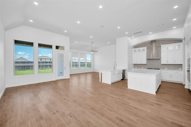 30218 Indigo Falls Dr, Brookshire, TX 77423 - kitchen featuring wall chimney exhaust hood, open floor plan, a center island with sink, light countertops, and vaulted ceiling
