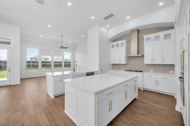 30218 Indigo Falls Dr, Brookshire, TX 77423 - kitchen with wall chimney range hood, a kitchen island, light wood-type flooring, a ceiling fan, and lofted ceiling