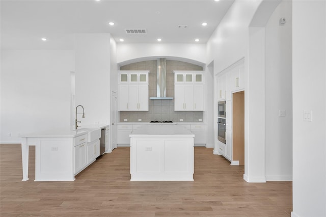 30218 Indigo Falls Dr, Brookshire, TX 77423 - kitchen featuring wall chimney range hood, a center island, light countertops, tasteful backsplash, and white cabinetry
