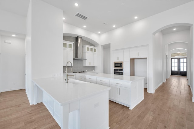 30218 Indigo Falls Dr, Brookshire, TX 77423 - kitchen with wall chimney exhaust hood, oven, french doors, a peninsula, and built in microwave