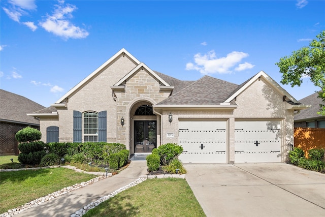5715 Caper Shores Ln, Sugar Land, TX 77479 - french country inspired facade with an attached garage, concrete driveway, stone siding, and french doors