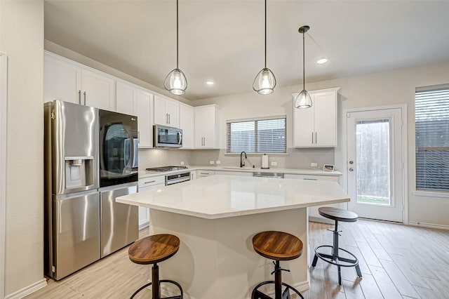 3226 Longleaf Meadows Dr, Houston, TX 77063 - kitchen featuring stainless steel appliances, a kitchen bar, light wood finished floors, a center island, and light countertops
