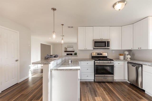 12707 Pleasant Grove Rd, Cypress, TX 77429 - kitchen with stainless steel appliances, a peninsula, dark wood finished floors, white cabinets, and hanging light fixtures