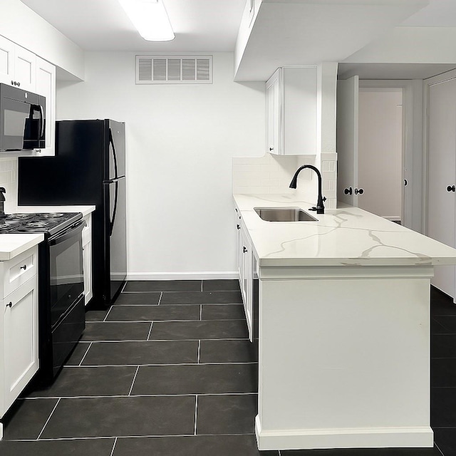 12905 Woodforest Blvd Unit 709, Houston, TX 77015 - kitchen featuring black appliances, a peninsula, light stone counters, white cabinetry, and dark tile patterned floors