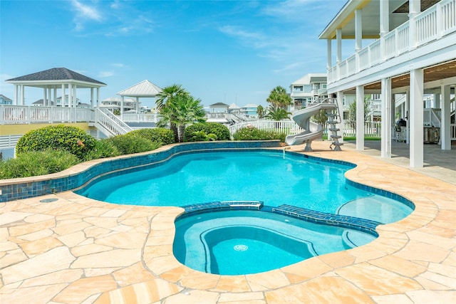 20611 E Sunset Bay Dr, Galveston, TX 77554 - view of swimming pool with a gazebo, a pool with connected hot tub, a water slide, a patio area, and stairs