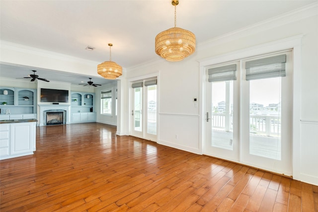 20611 E Sunset Bay Dr, Galveston, TX 77554 - unfurnished living room featuring ceiling fan, a chandelier, crown molding, light wood-type flooring, and a fireplace