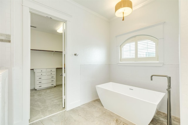 20611 E Sunset Bay Dr, Galveston, TX 77554 - bathroom featuring a soaking tub, tile walls, a walk in closet, crown molding, and a wainscoted wall