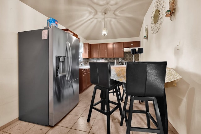 1318 Des Jardines St, Houston, TX 77023 - kitchen with stainless steel fridge, backsplash, light countertops, decorative light fixtures, and brown cabinets