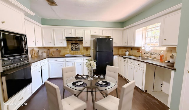 9518 Langdon Ln, Houston, TX 77036 - kitchen featuring black appliances, white cabinetry, tasteful backsplash, under cabinet range hood, and dark countertops