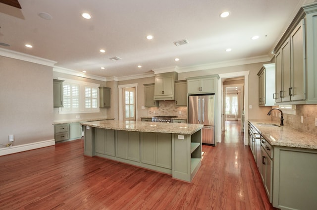 626 E 22nd St, Houston, TX 77008 - kitchen featuring stainless steel refrigerator, a spacious island, wood finished floors, crown molding, and decorative backsplash