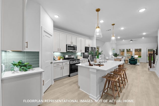 20530 Draper Rd, Tomball, TX 77377 - kitchen featuring appliances with stainless steel finishes, light wood-style floors, a kitchen island with sink, open floor plan, and white cabinets