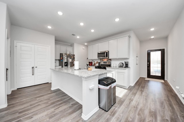 23238 Spring Genesis Ln, Katy, TX 77493 - kitchen featuring stainless steel appliances, light wood-type flooring, recessed lighting, an island with sink, and white cabinets