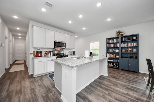 23238 Spring Genesis Ln, Katy, TX 77493 - kitchen with appliances with stainless steel finishes, dark wood-style flooring, white cabinets, an island with sink, and recessed lighting