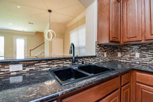 14431 Basalt Ln, Houston, TX 77077 - kitchen with ornamental molding, decorative backsplash, brown cabinetry, dark stone countertops, and decorative light fixtures