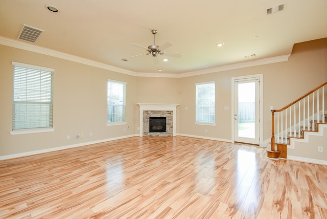 14431 Basalt Ln, Houston, TX 77077 - unfurnished living room featuring a ceiling fan, crown molding, light wood finished floors, a stone fireplace, and stairs
