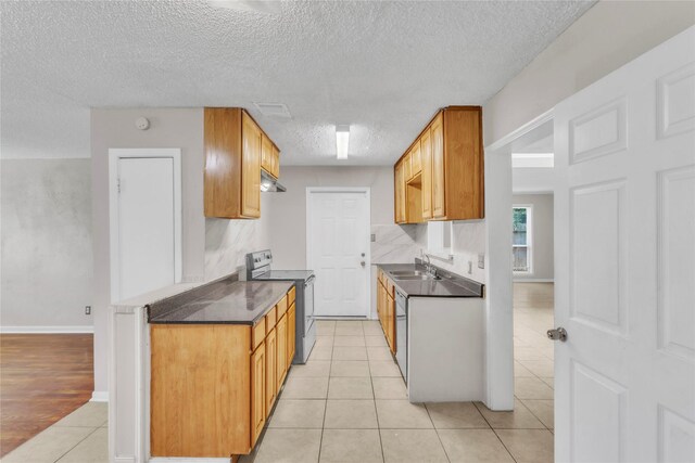 11515 Duane St, Houston, TX 77047 - kitchen with electric stove, dark countertops, a textured ceiling, under cabinet range hood, and light tile patterned floors