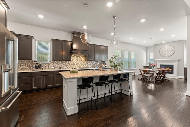 22 Mayapple Blossom Pl, Tomball, TX 77375 - kitchen featuring high quality fridge, custom range hood, backsplash, dark wood-style floors, and a kitchen breakfast bar