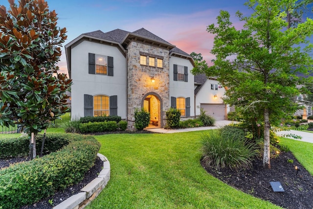 22 Mayapple Blossom Pl, Tomball, TX 77375 - french country style house featuring stone siding, a front yard, stucco siding, concrete driveway, and a garage