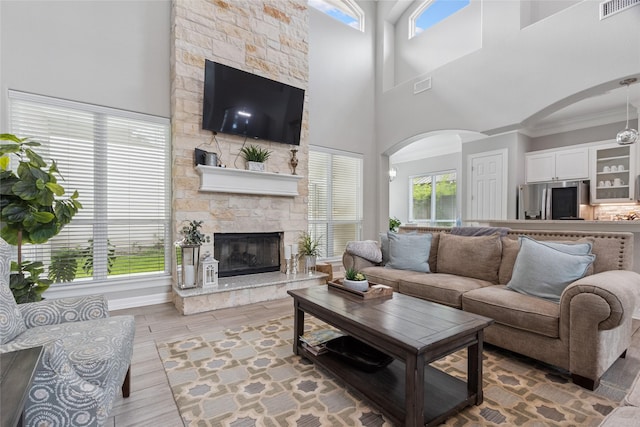 4511 Palo Pinto Dr, Houston, TX 77041 - living room featuring arched walkways, crown molding, a fireplace, light wood-style flooring, and a towering ceiling