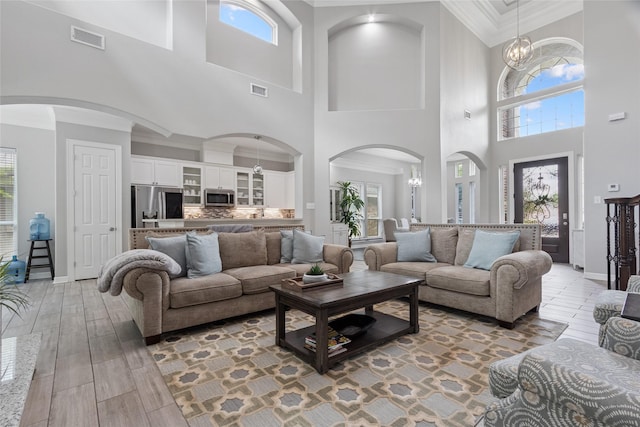 4511 Palo Pinto Dr, Houston, TX 77041 - living room featuring a high ceiling, healthy amount of natural light, arched walkways, light wood-style floors, and a chandelier