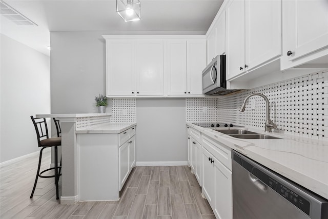 4511 Palo Pinto Dr, Houston, TX 77041 - kitchen featuring appliances with stainless steel finishes, decorative backsplash, light stone counters, white cabinetry, and a kitchen bar