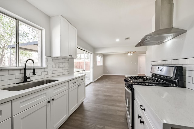 1310 Beaver Bend Rd, Houston, TX 77088 - kitchen featuring wall chimney range hood, stainless steel range with gas stovetop, tasteful backsplash, wood finished floors, and recessed lighting