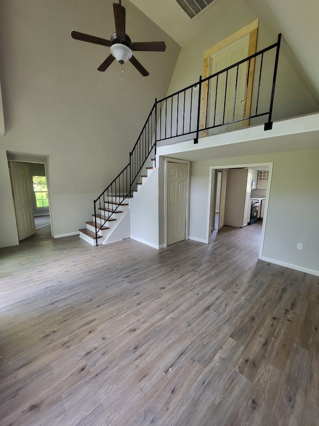 4520 County Road 929c, Brazoria, TX 77422 - unfurnished living room featuring high vaulted ceiling, a ceiling fan, stairway, and wood finished floors