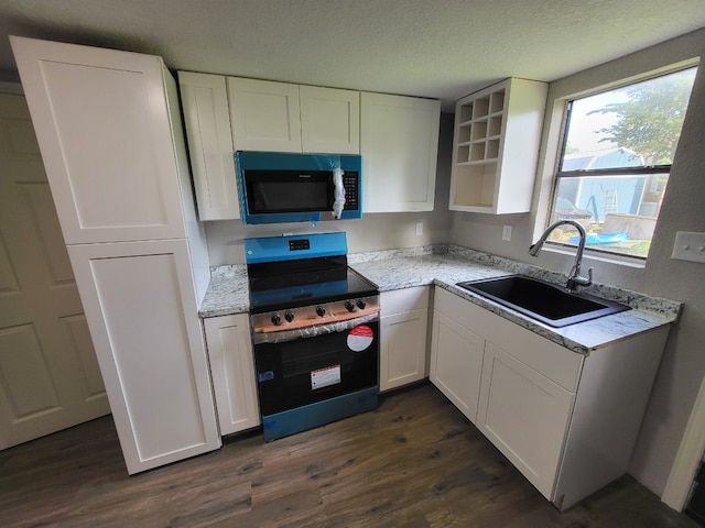 4520 County Road 929c, Brazoria, TX 77422 - kitchen with stainless steel microwave, stove, white cabinetry, dark wood-style flooring, and a textured ceiling