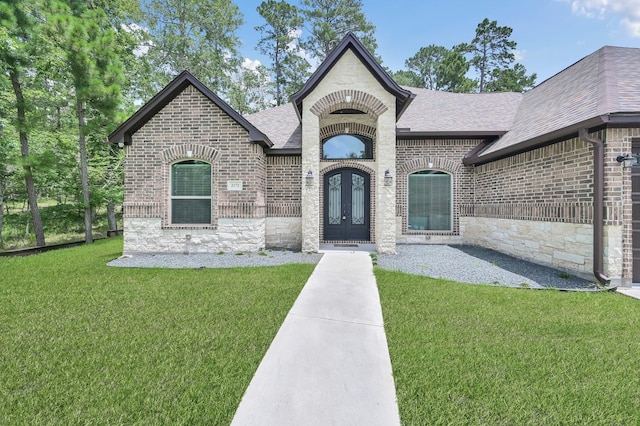 2172 Greentree Dr, Huntsville, TX 77340 - french country home featuring roof with shingles, brick siding, french doors, a front lawn, and stone siding