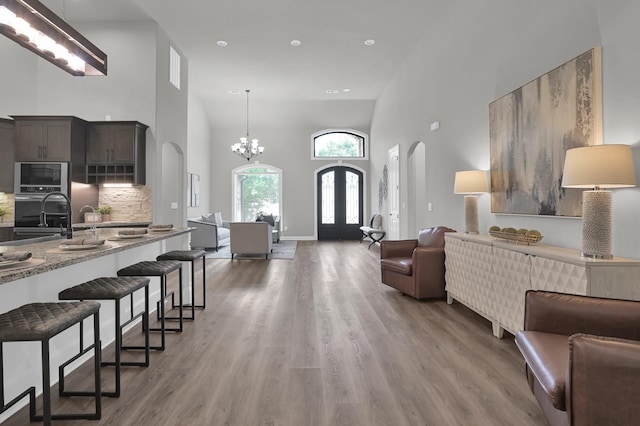 2172 Greentree Dr, Huntsville, TX 77340 - living room with arched walkways, a towering ceiling, light wood finished floors, a chandelier, and recessed lighting
