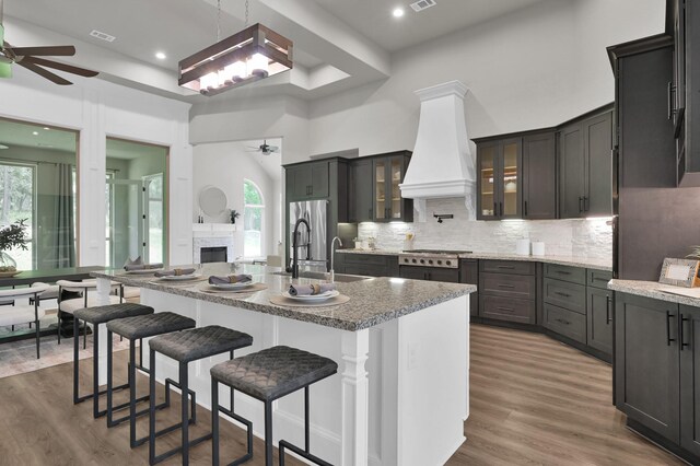 2172 Greentree Dr, Huntsville, TX 77340 - kitchen with a ceiling fan, premium range hood, decorative backsplash, appliances with stainless steel finishes, and wood finished floors