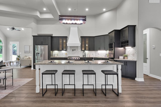 2172 Greentree Dr, Huntsville, TX 77340 - kitchen with stainless steel appliances, premium range hood, a breakfast bar area, a ceiling fan, and a high ceiling