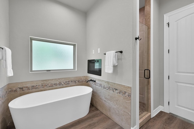 2172 Greentree Dr, Huntsville, TX 77340 - bathroom with a soaking tub, a stall shower, tile walls, wood finished floors, and a wainscoted wall