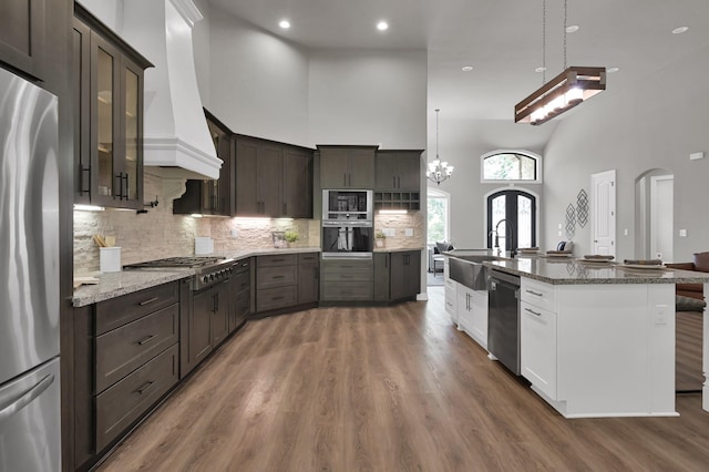 2172 Greentree Dr, Huntsville, TX 77340 - kitchen featuring appliances with stainless steel finishes, arched walkways, a high ceiling, dark brown cabinets, and wood finished floors