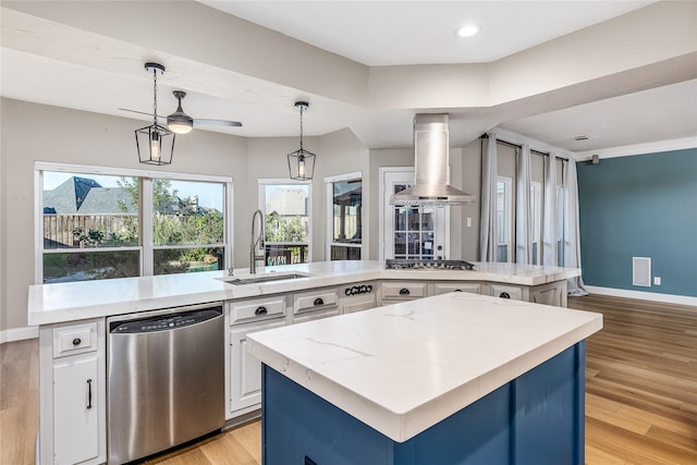 1526 Pecan Crossing Dr, Richmond, TX 77406 - kitchen featuring stainless steel appliances, wall chimney range hood, a center island, white cabinetry, and light wood-style floors