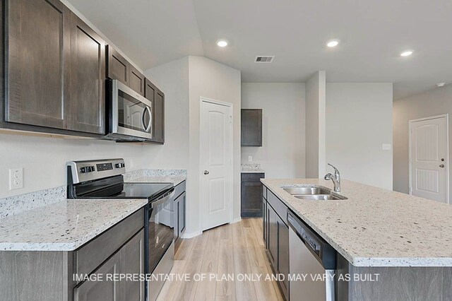 217 Rockbridge Dr, Huntsville, TX 77340 - kitchen featuring appliances with stainless steel finishes, light wood-type flooring, dark brown cabinetry, a center island with sink, and recessed lighting