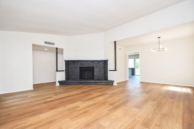 14511 Lourdes Dr, Houston, TX 77049 - unfurnished living room featuring a chandelier, light wood finished floors, and a brick fireplace