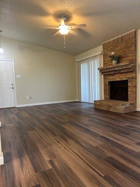 10555 Turtlewood Ct Unit 2111, Houston, TX 77072 - unfurnished living room with a ceiling fan, a textured ceiling, dark wood-style flooring, and a fireplace