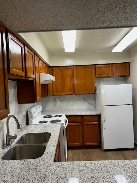 10555 Turtlewood Ct Unit 2111, Houston, TX 77072 - kitchen with white appliances, under cabinet range hood, brown cabinetry, and decorative backsplash