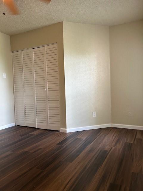10555 Turtlewood Ct Unit 2111, Houston, TX 77072 - unfurnished bedroom featuring dark wood-style flooring, a textured ceiling, a closet, and a ceiling fan